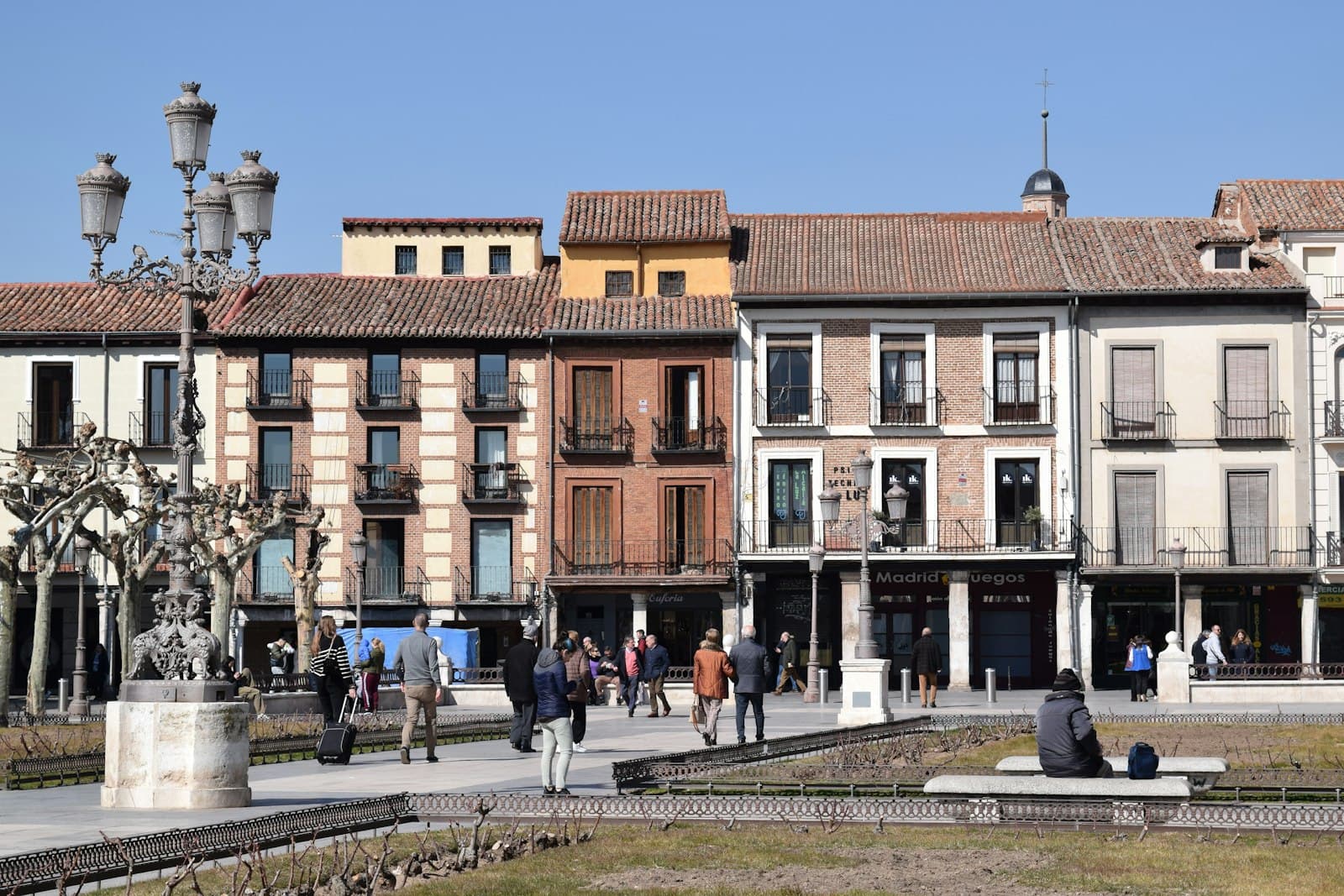 Alcalá de Henares — a group of people walking down a street next to tall buildings