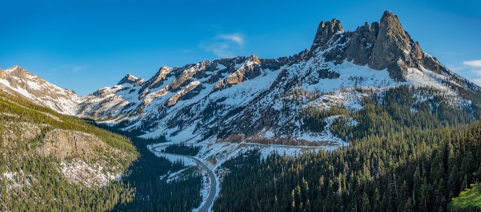 Alpine — a snow covered mountain with a winding road in the foreground
