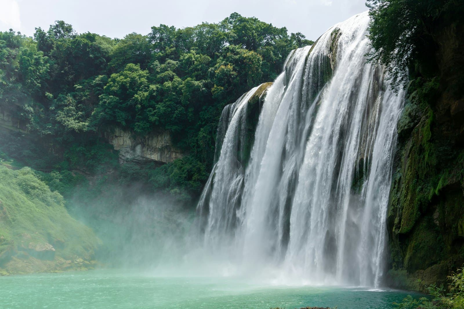 Anshun — A majestic waterfall flows into a turquoise pool.