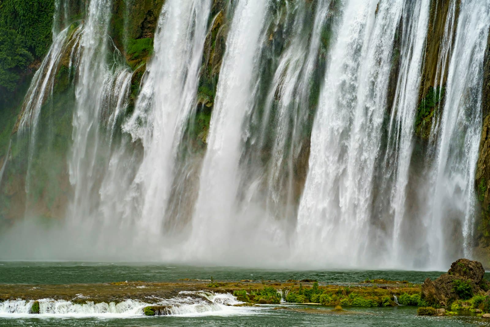 Anshun — A man riding a horse in front of a waterfall