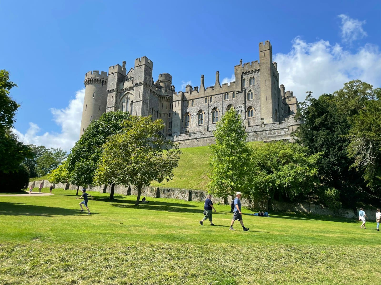 Arundel — people walking on green grass field near brown concrete building during daytime