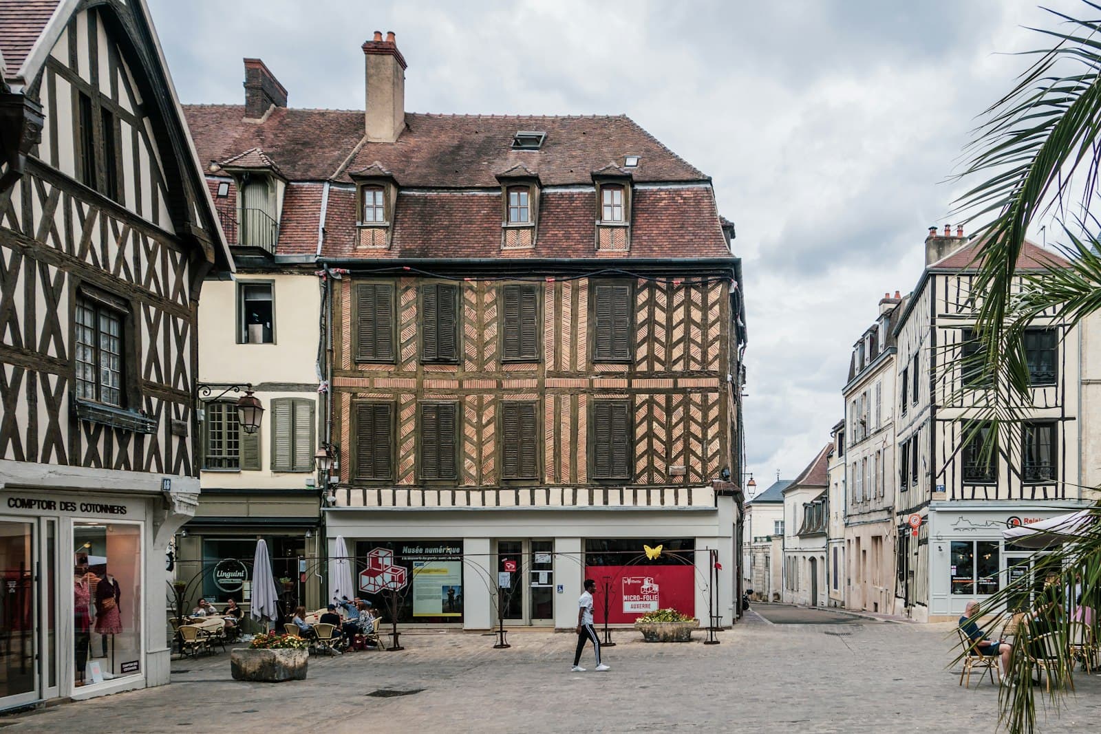 Auxerre — a man walking down a street next to tall buildings