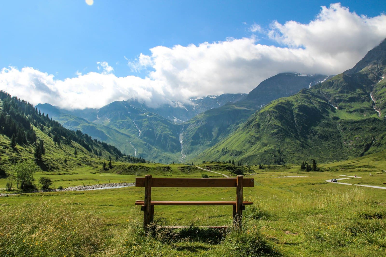 Bad Gastein — a wooden bench sitting on top of a lush green field