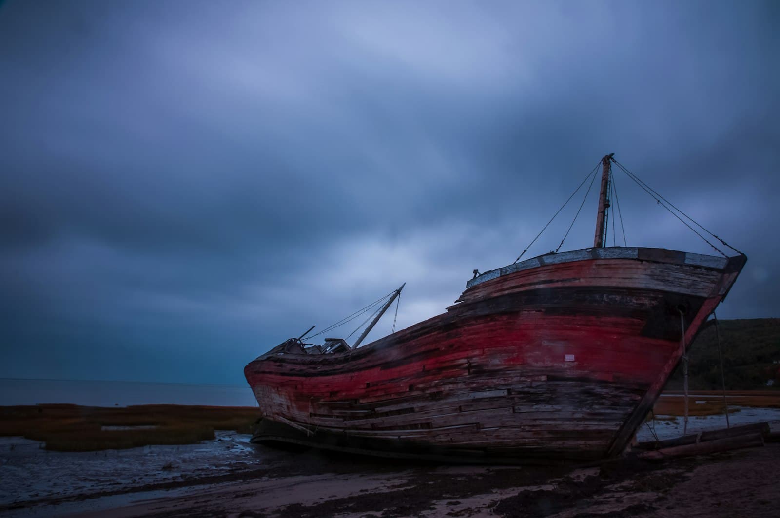 Baie-Saint-Paul — a boat sitting on top of a beach under a cloudy sky