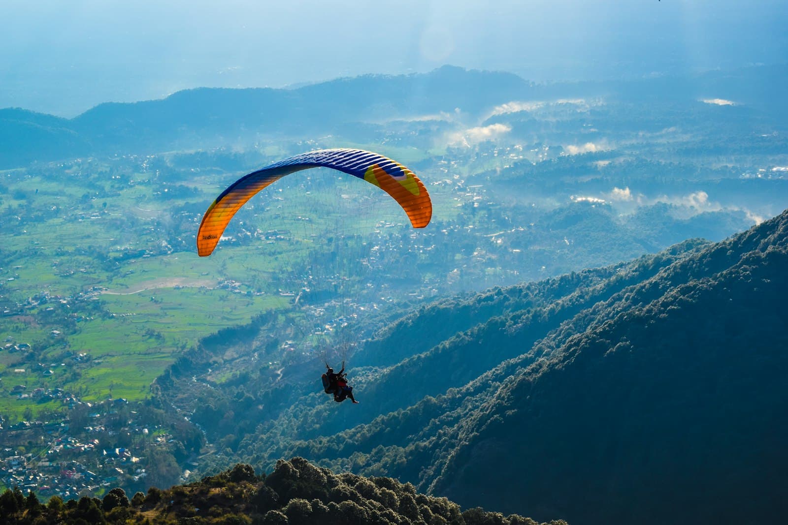 Bir — person in black shirt with yellow parachute over the mountains during daytime