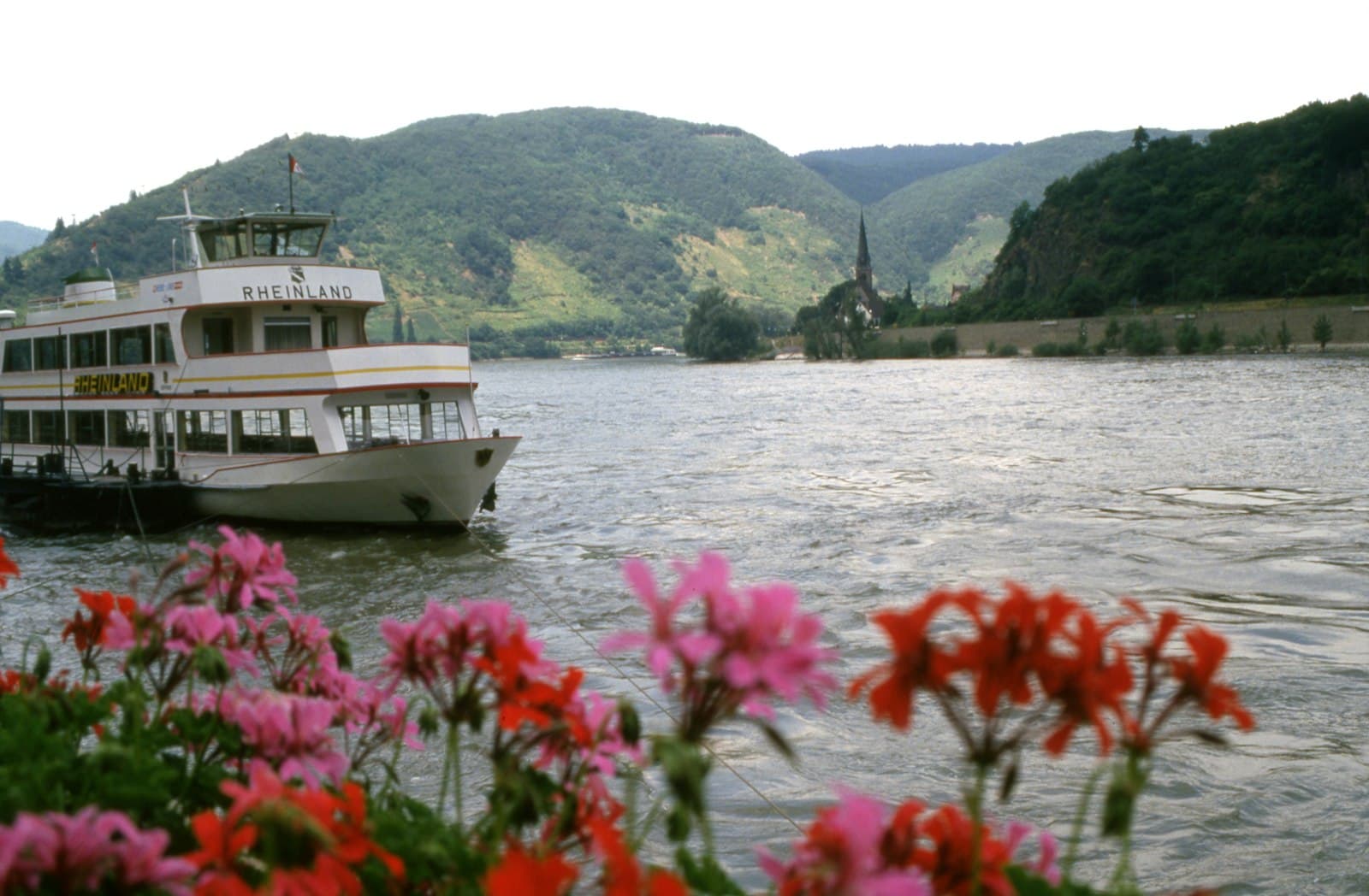Boppard — A boat floating on top of a river next to a lush green hillside