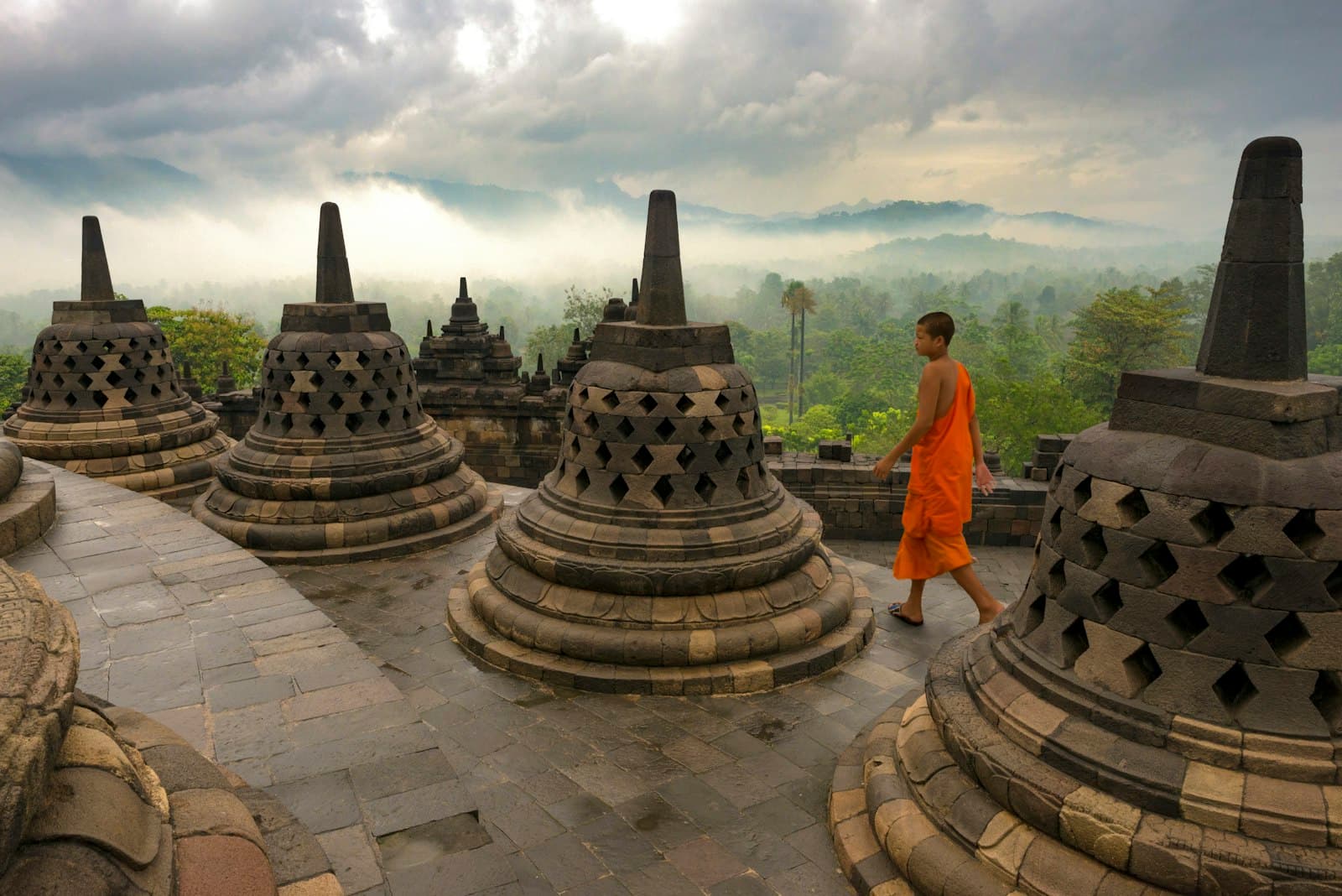 Borobudur — man in orange shirt standing near gold buddha statue