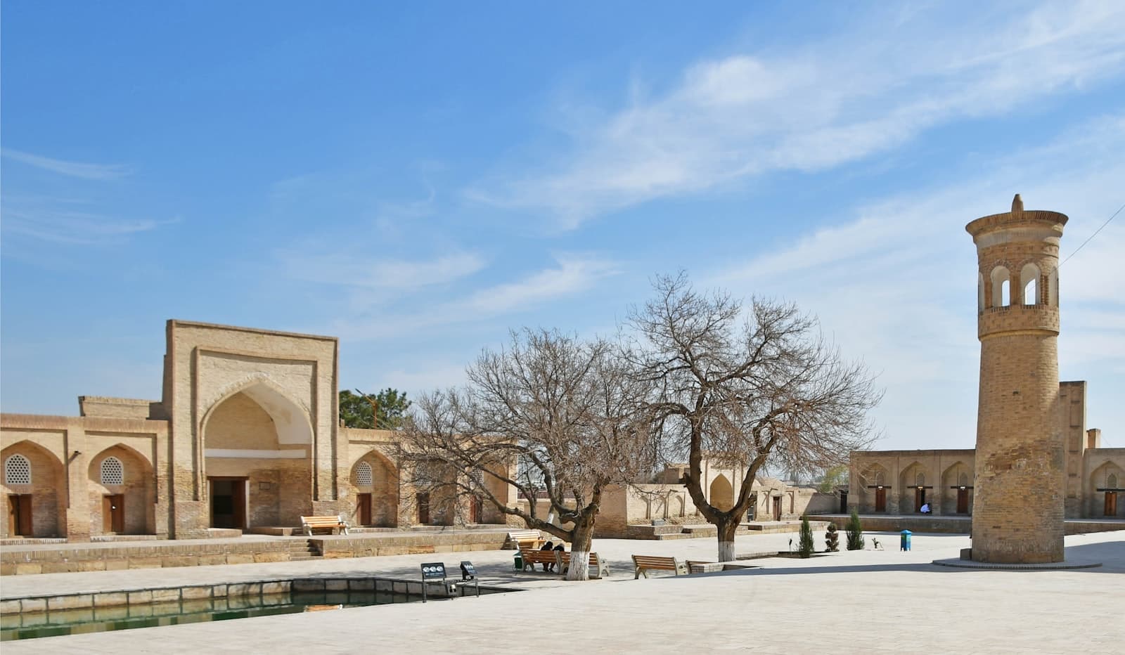 Boukhara — the courtyard of a building with a clock tower in the background