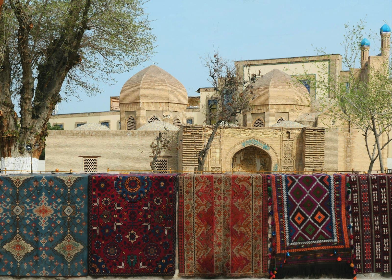 Boukhara — Carpets are displayed in front of an ancient building.