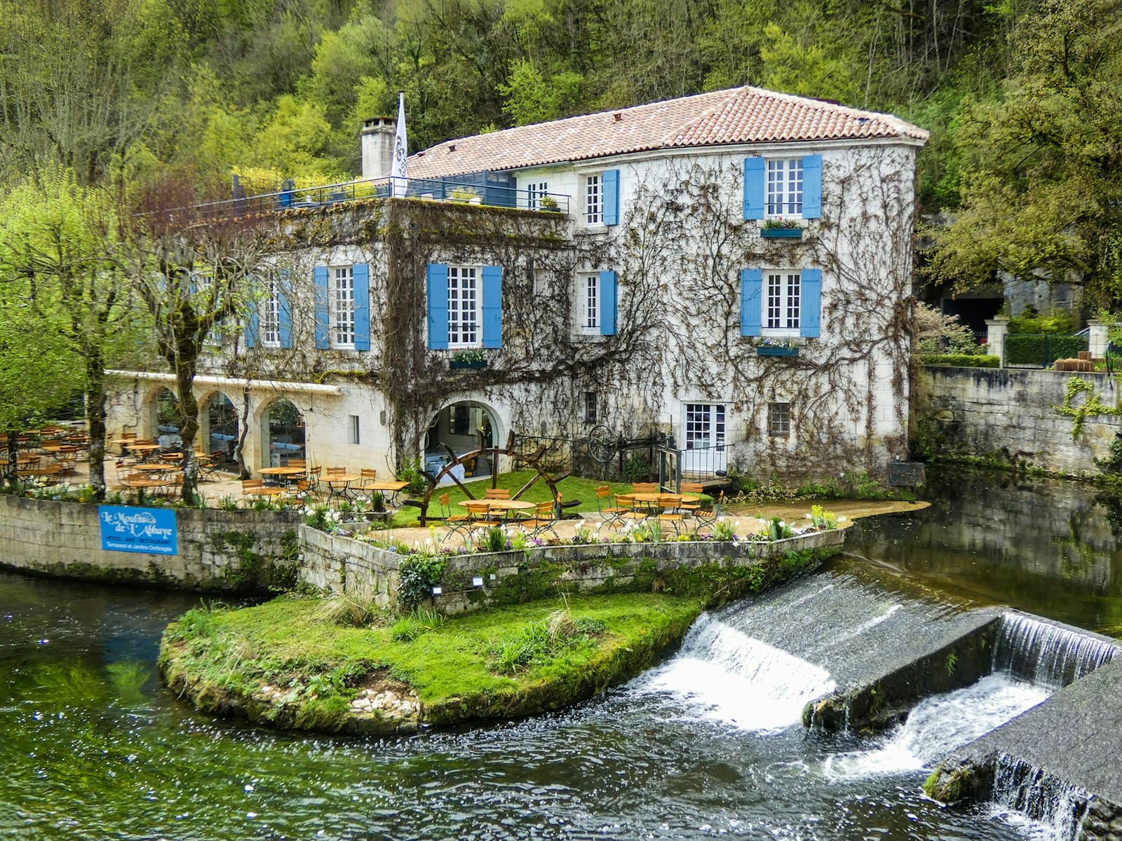 Brantôme — a building with blue shutters next to a river