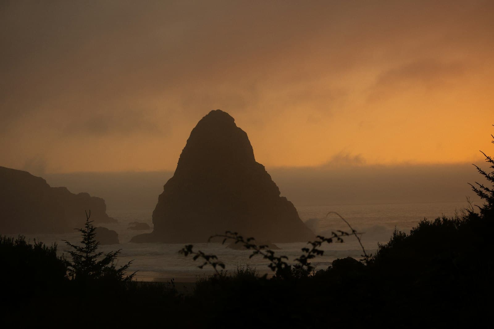 Brookings — the sun is setting over the ocean with a rock in the foreground