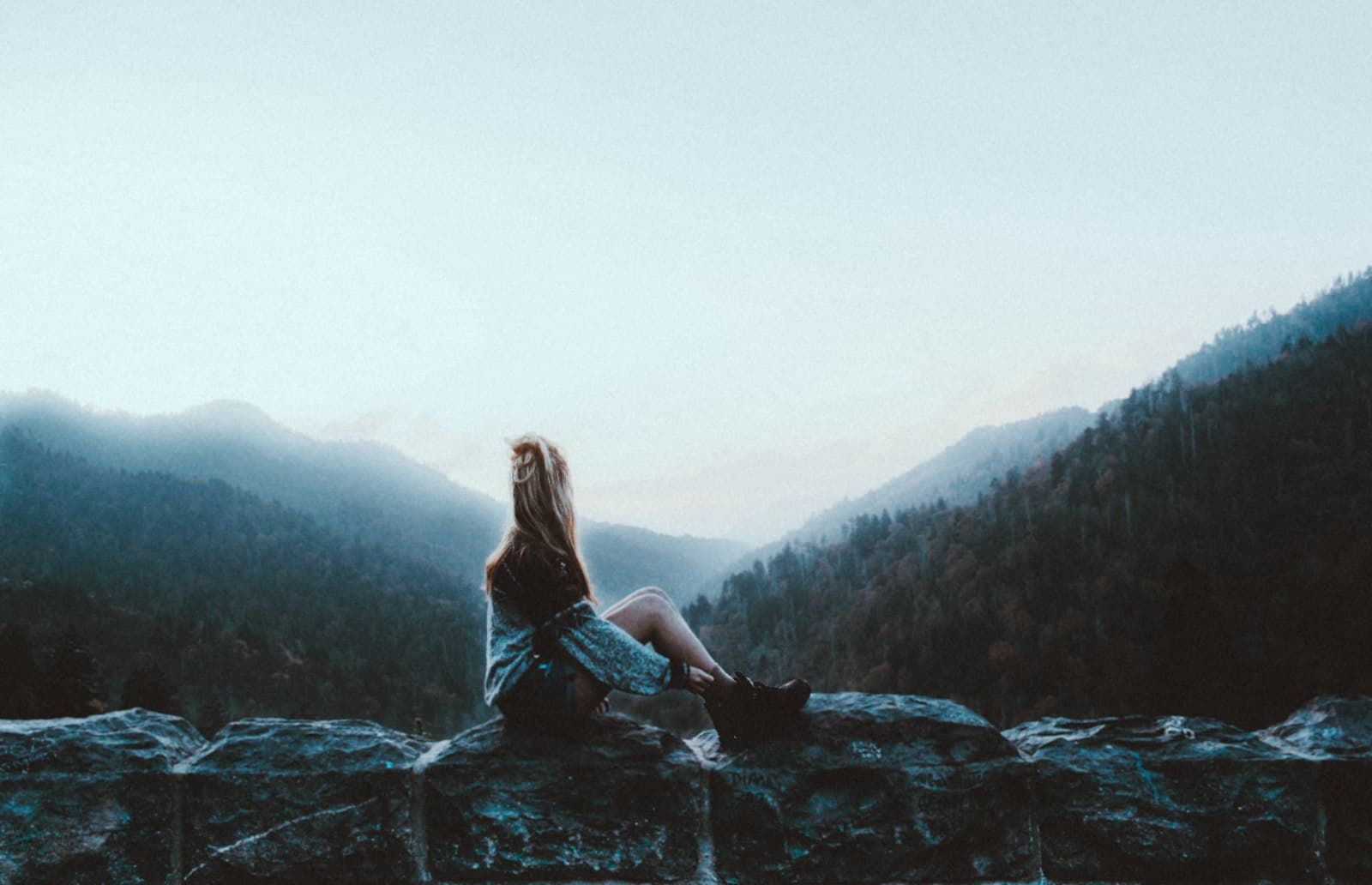 Bryson City — woman sitting on gray rock facing green mountains