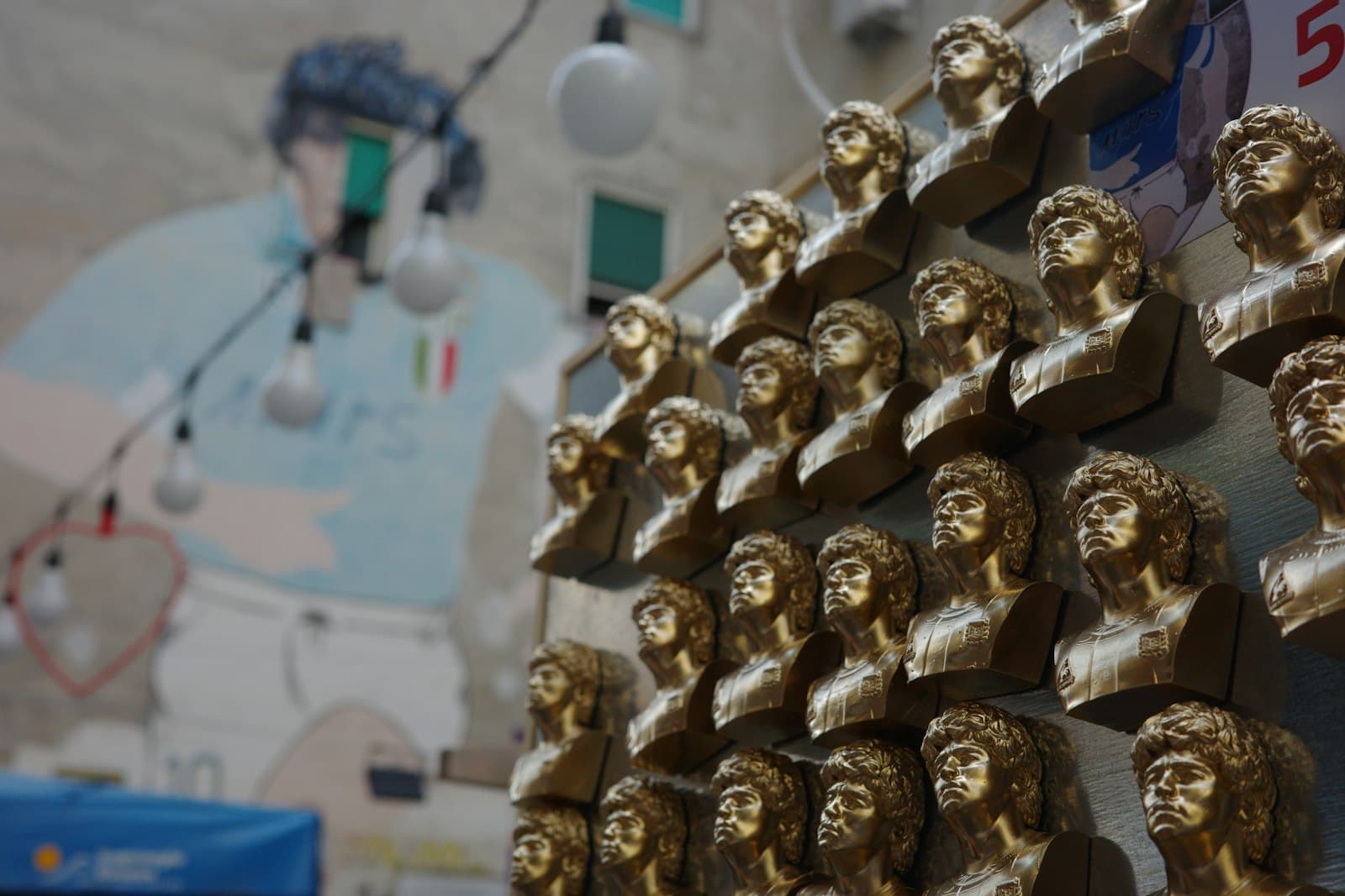 Busto Arsizio — Golden busts arranged on a wall with a blurred mural