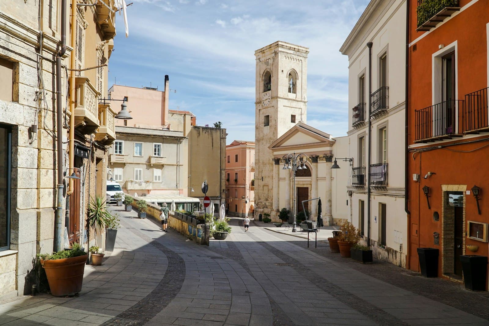 Cagliari — a narrow street with a clock tower in the background