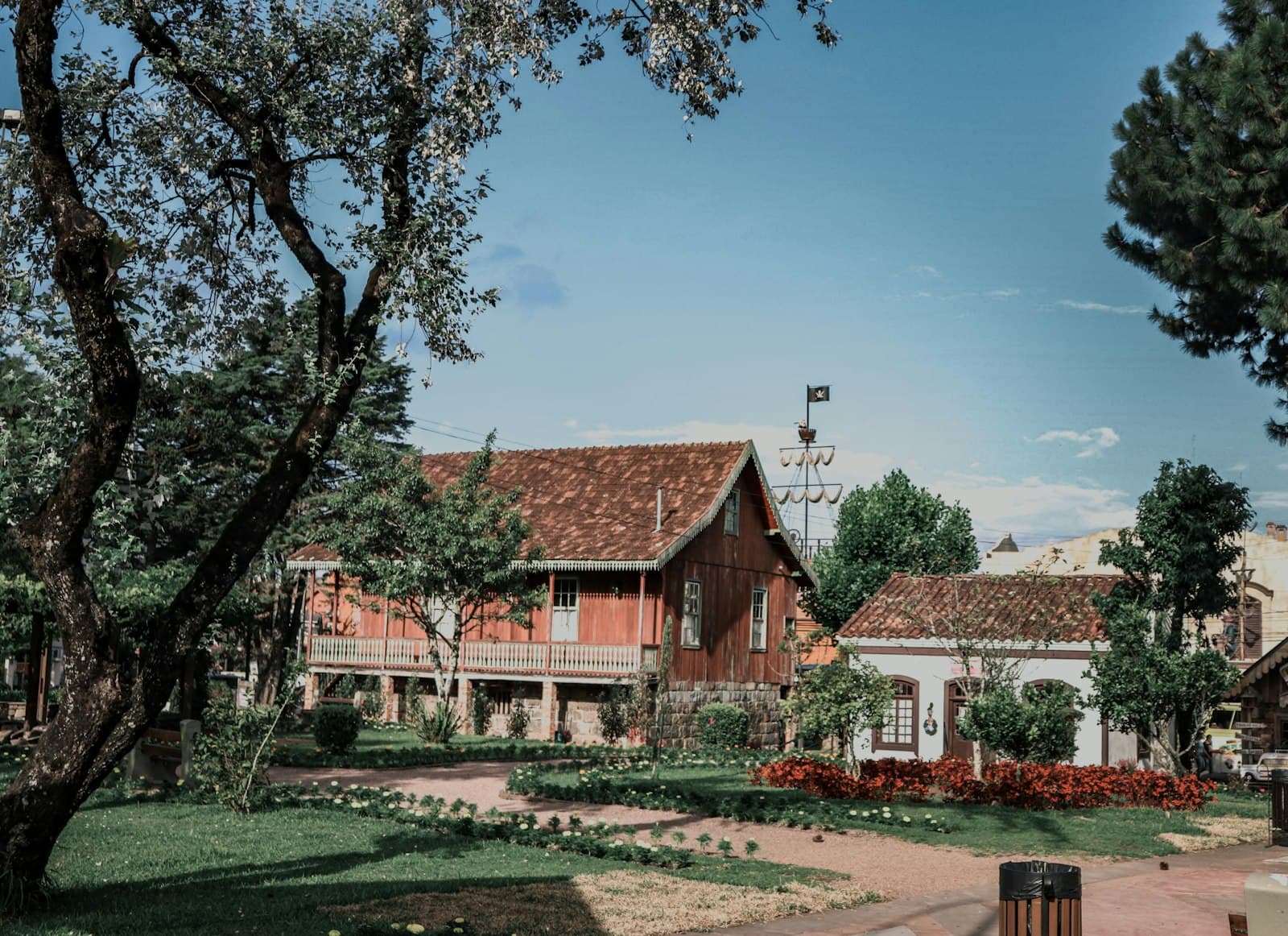Canela — red and white concrete house near green trees under blue sky during daytime