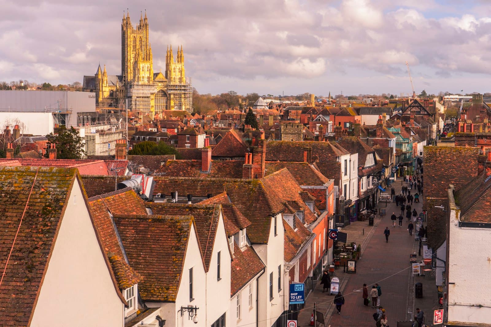 Canterbury — a group of people walking down a street next to tall buildings