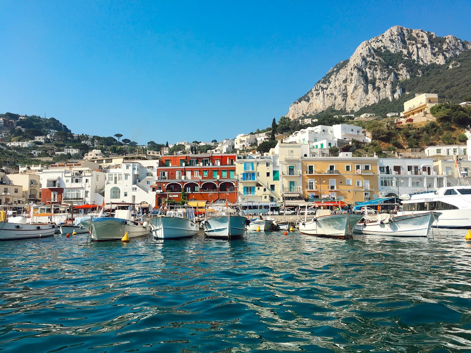 Capri — white and brown boat on body of water near city buildings during daytime
