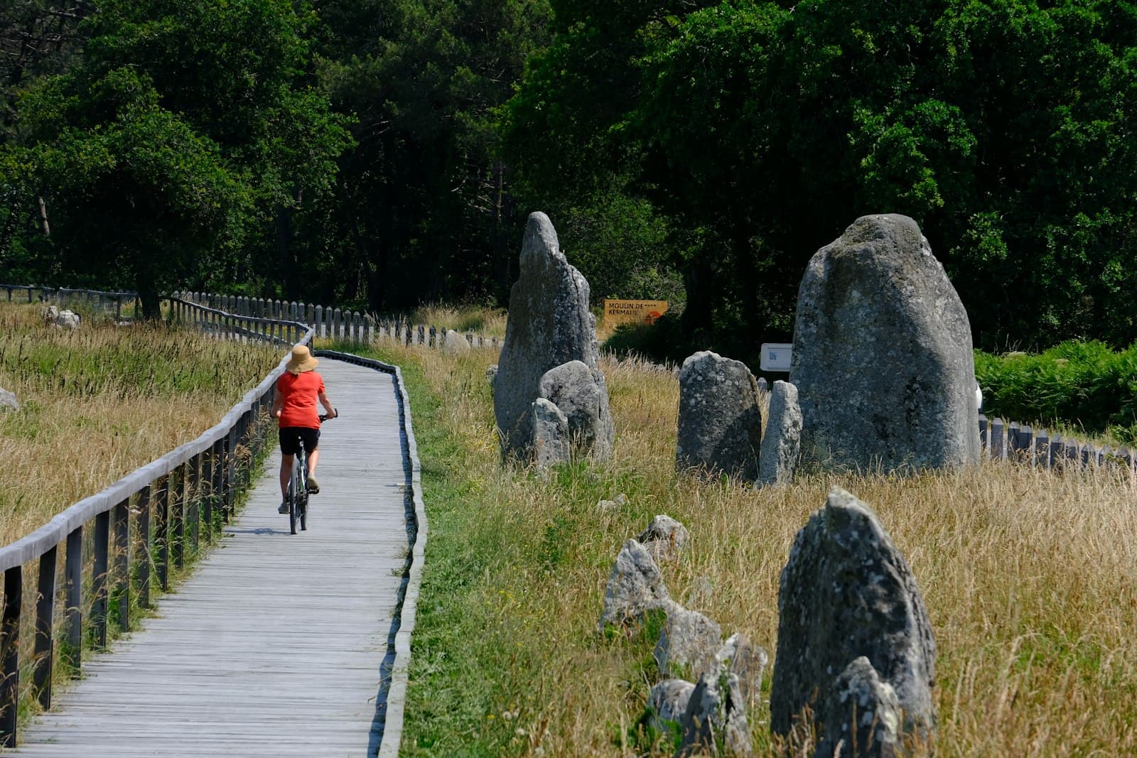 Carnac — a woman riding a bike down a wooden path
