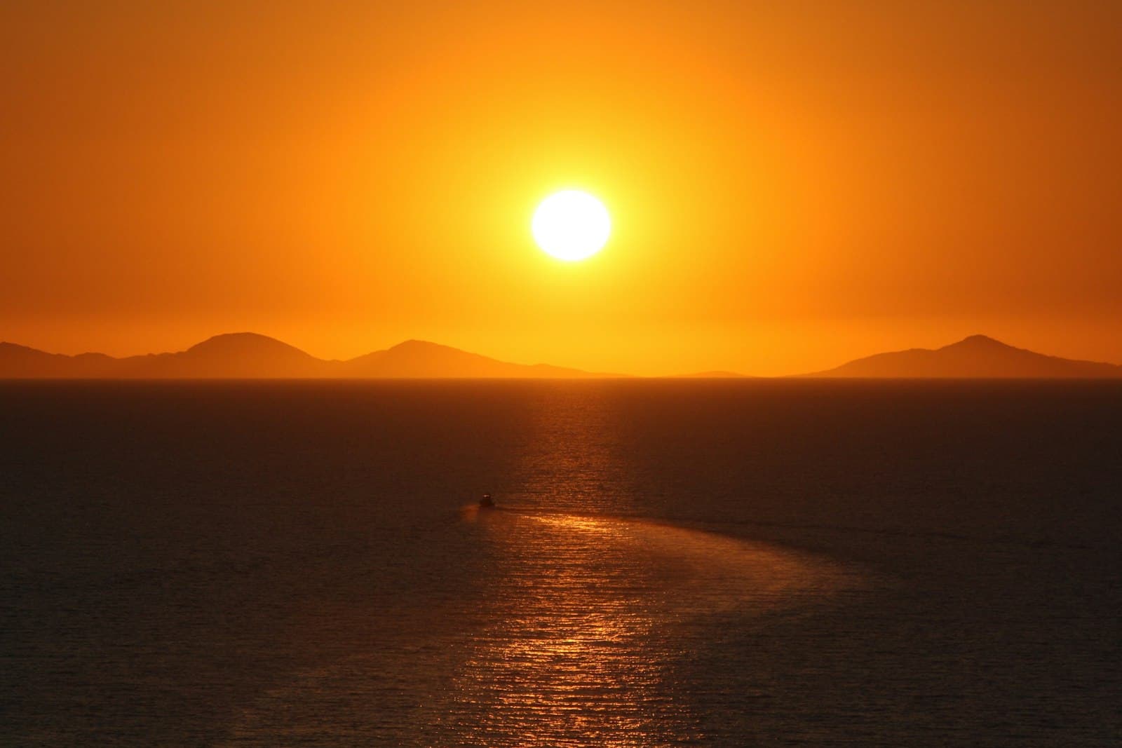 Castelsardo — the sun is setting over the ocean with a boat in the water