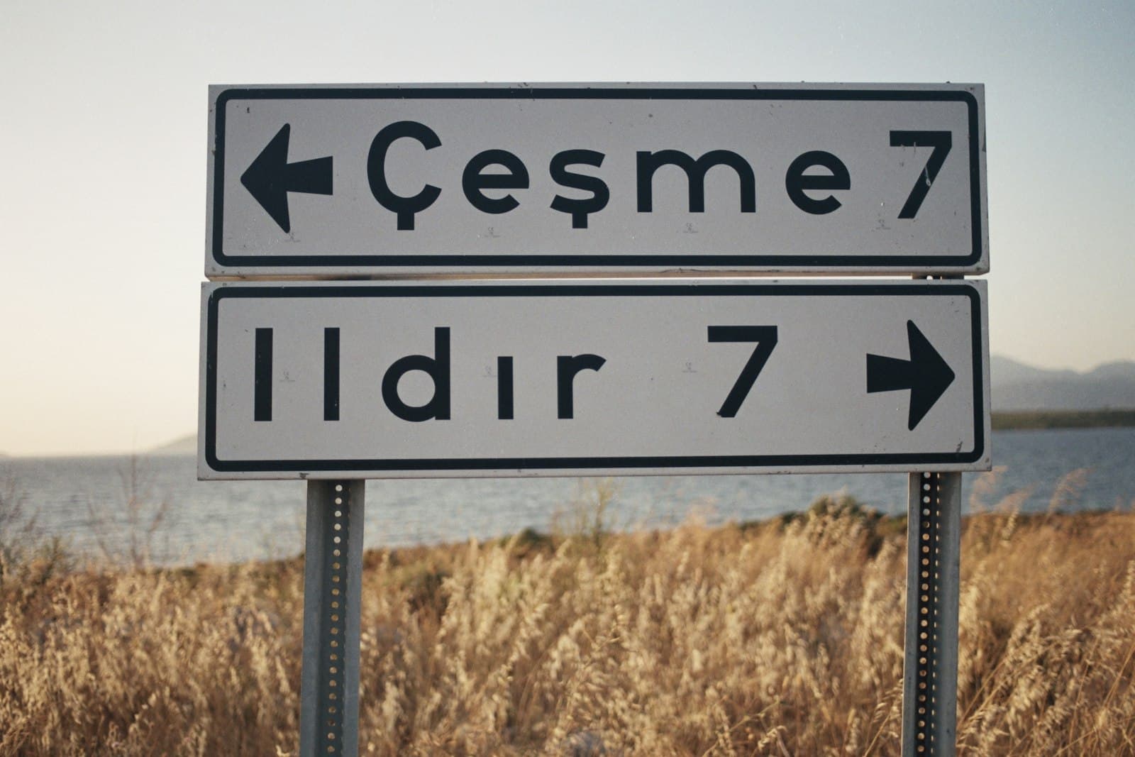 Çeşme — a couple of street signs sitting in front of a body of water