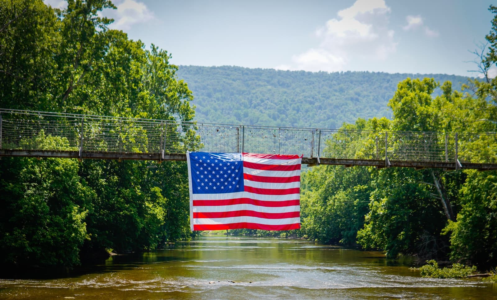 Charlevoix — An american flag hangs from a bridge over a river.