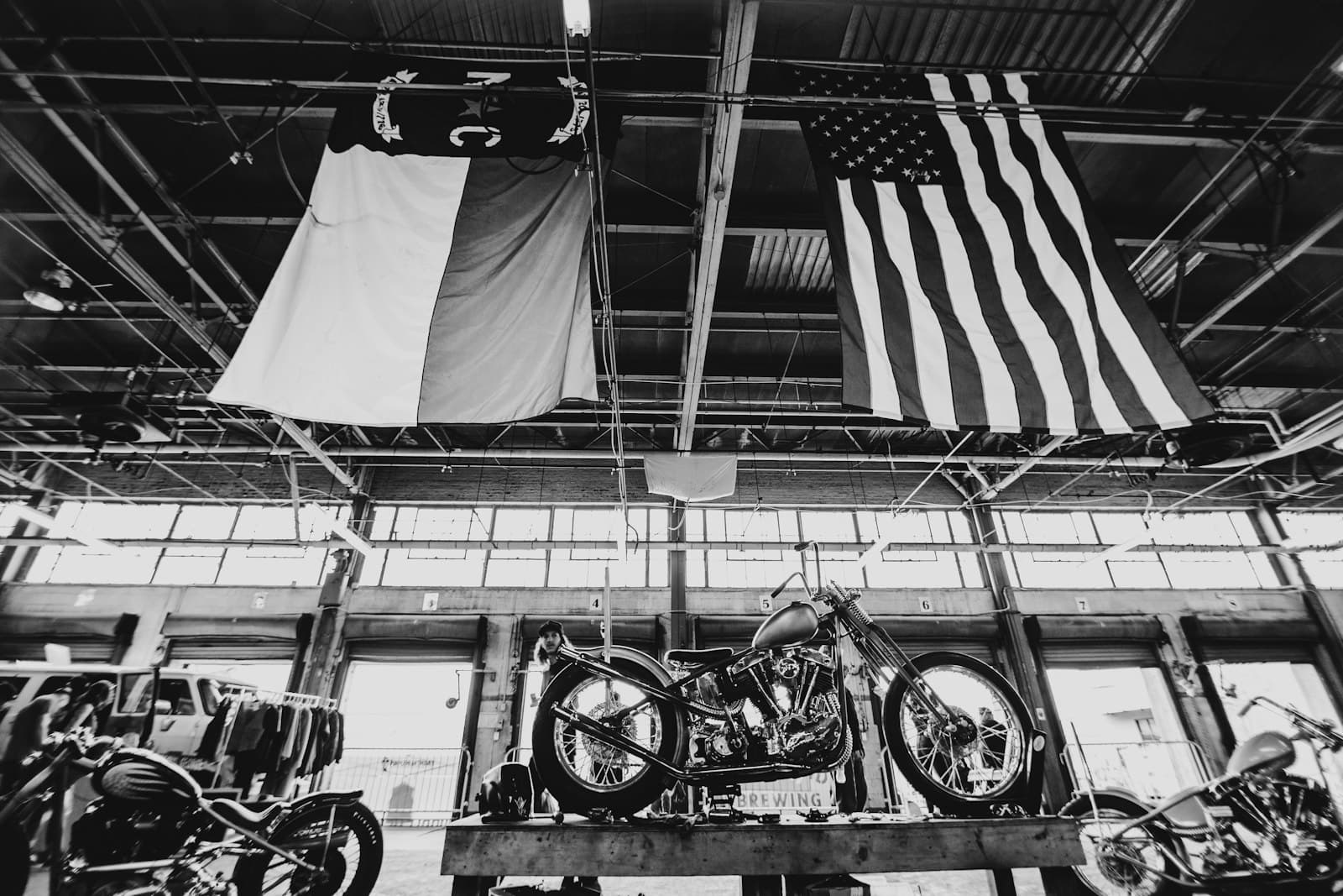 Charlotte — grayscale photo of a motorcycle and a flag of us a on a pole
