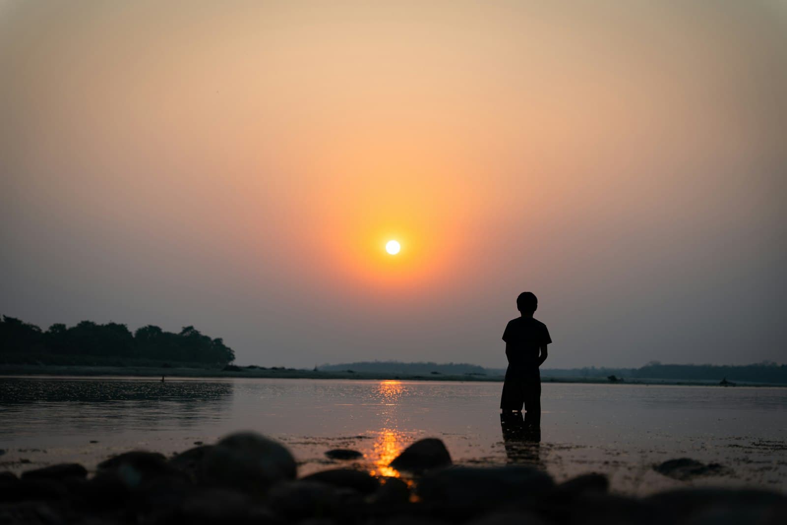 Chitwan — Person stands in water watching the beautiful sunset.