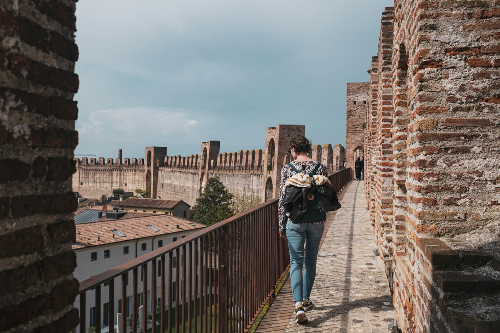Cittadella — a man walking down a brick walkway next to a brick wall