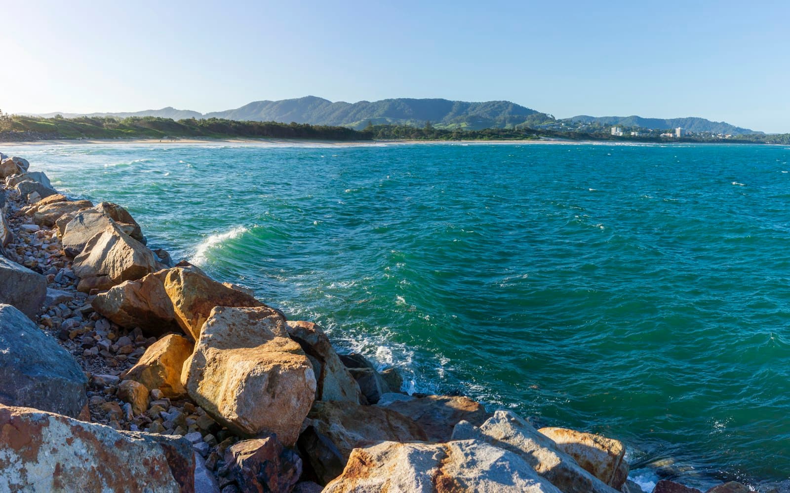 Coffs Harbour — brown rocky shore with green sea water in the distance