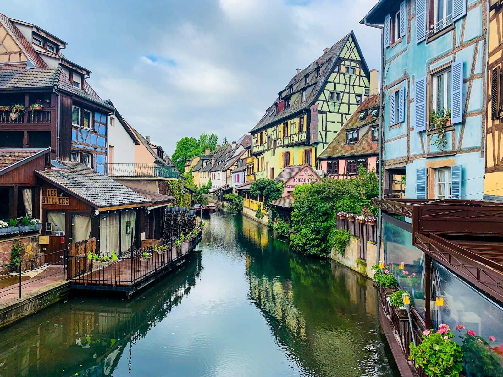 Colmar — brown and white concrete buildings beside river under white clouds during daytime