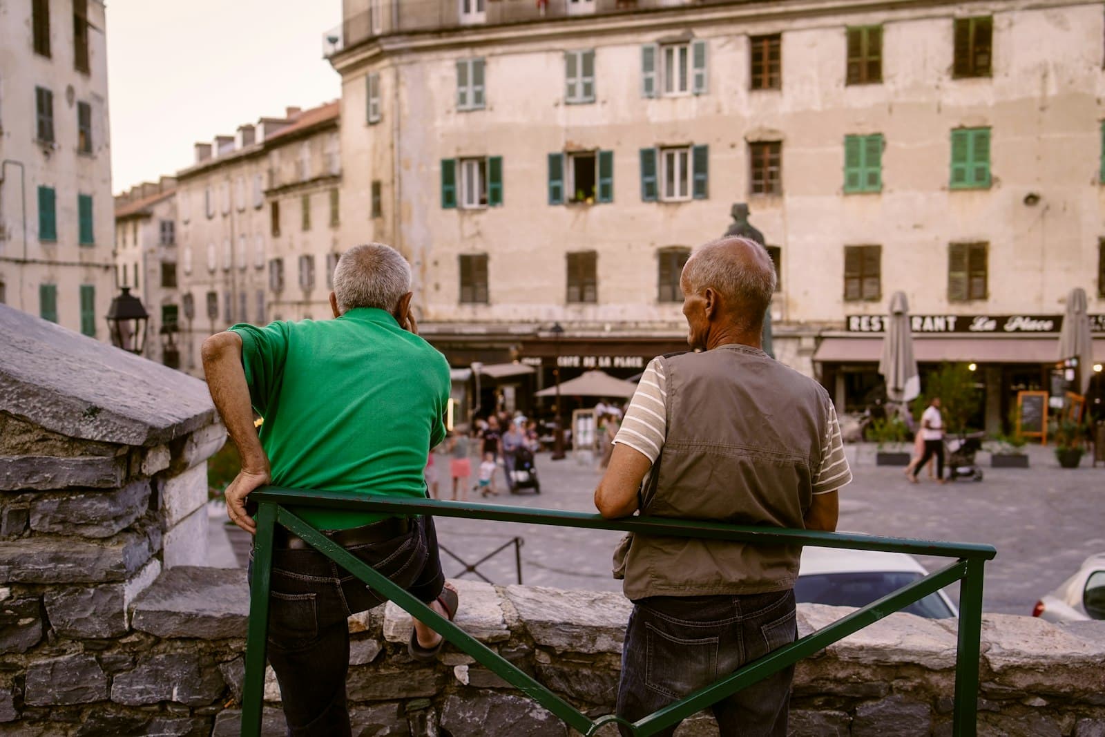 Corte — a couple of men sitting on a bench looking at a building
