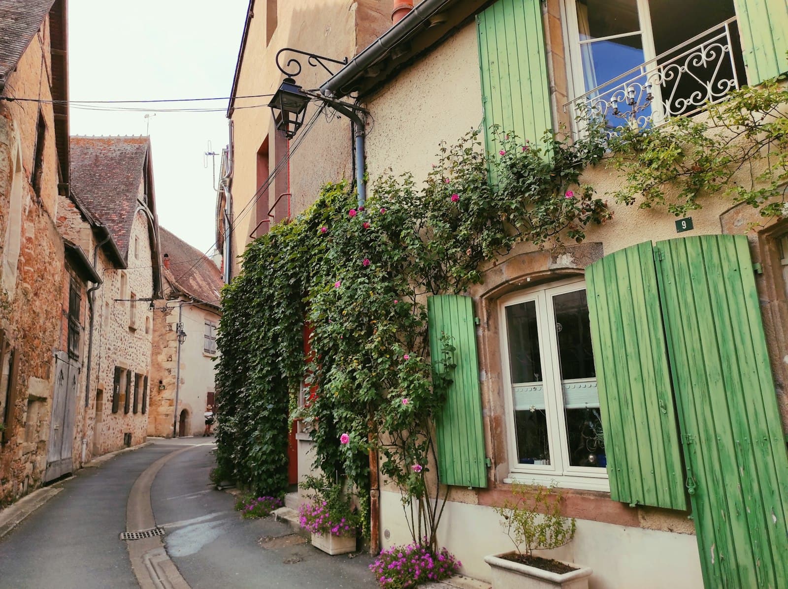 Crécy-en-Ponthieu — a row of houses with green shutters and a green curtain
