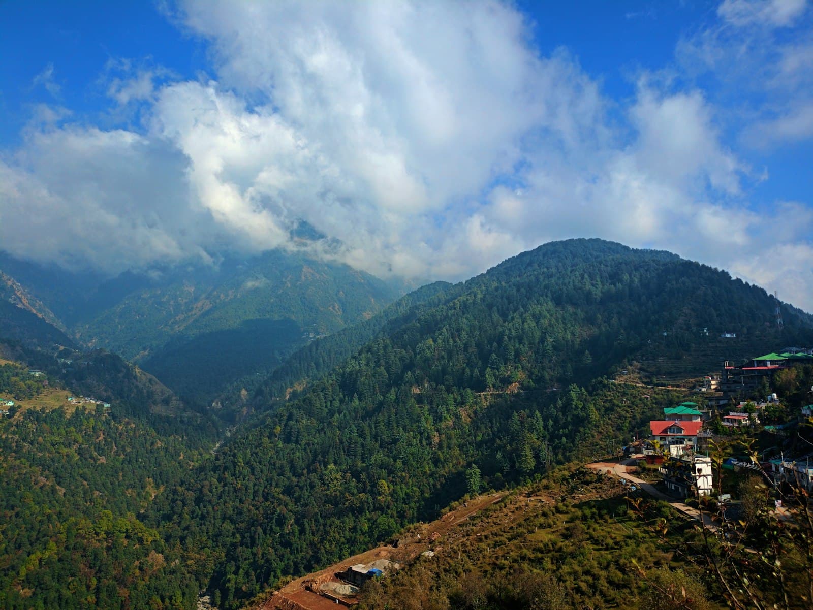 Dharamshala — a scenic view of a valley with a mountain in the background