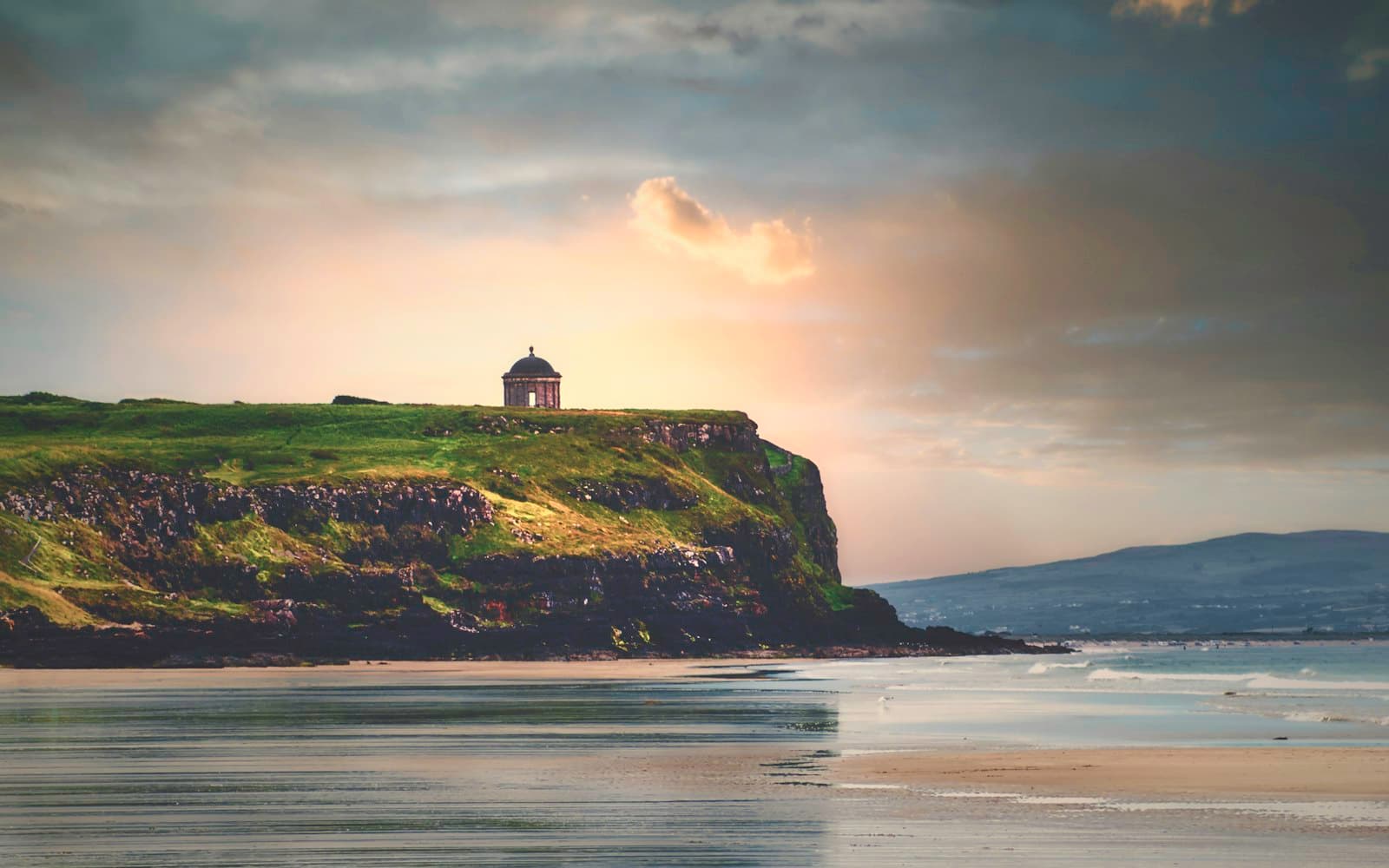 Donegal — silhouette of lighthouse on hill near body of water during daytime