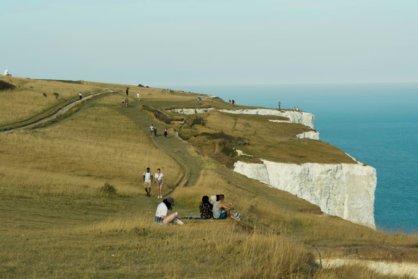 Dover — people sitting on green grass field near body of water during daytime