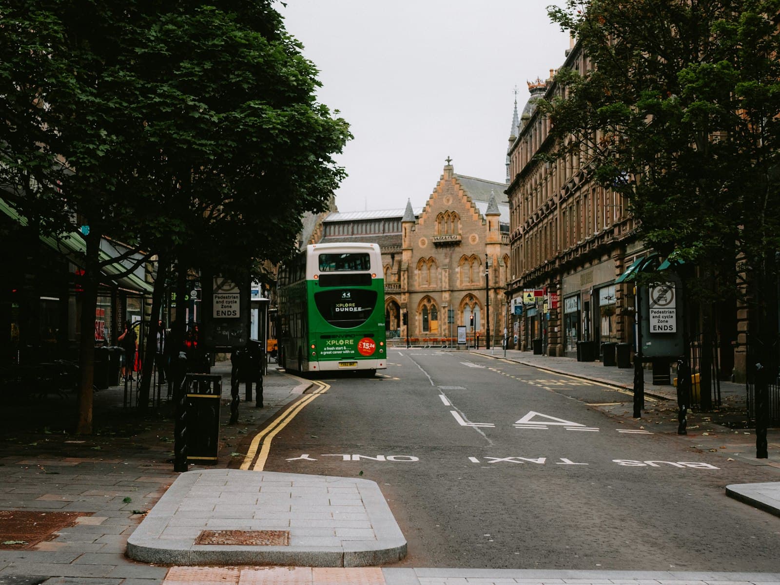 Dundee — A green bus driving down a street next to tall buildings