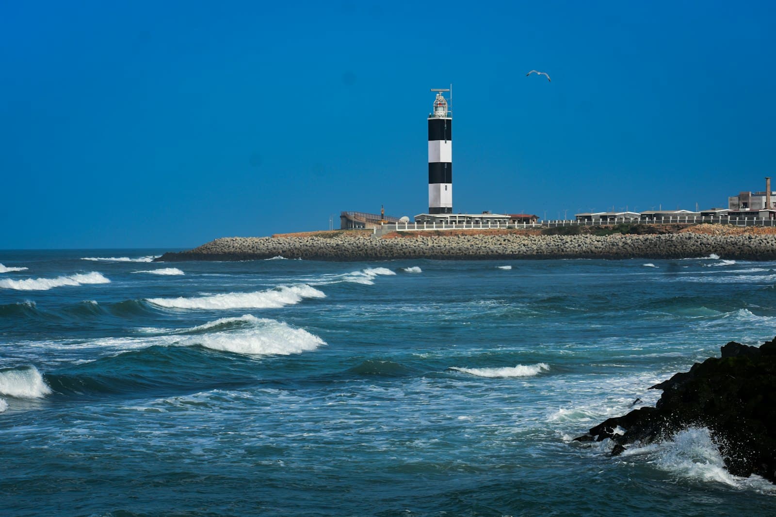 Dwarka — a black and white lighthouse on a rocky shore