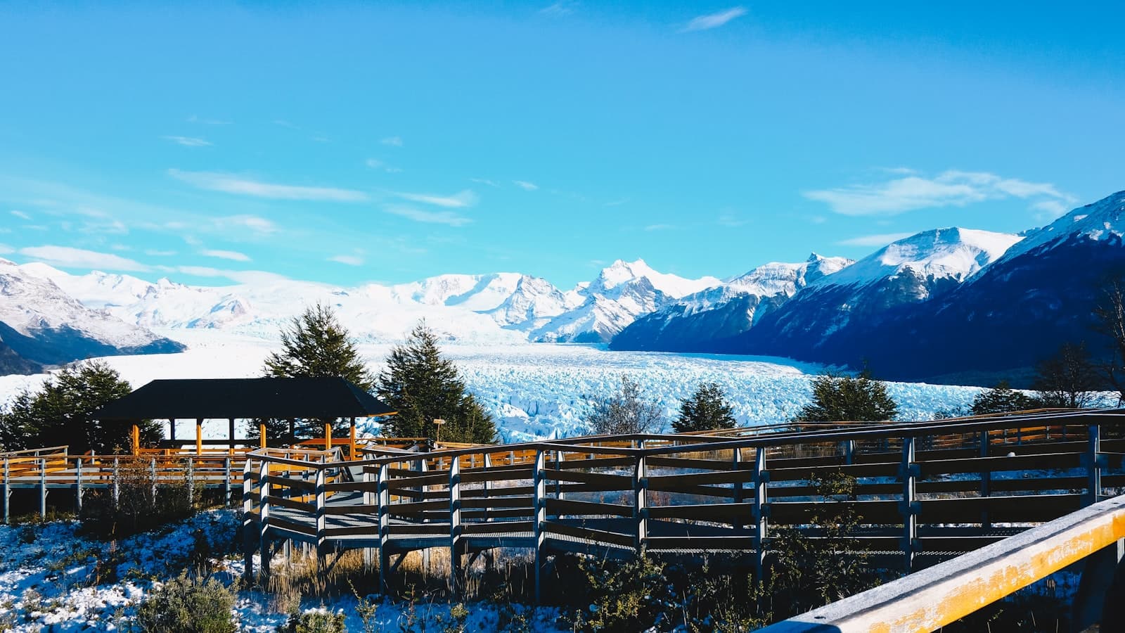 El Calafate — brown wooden fence on green grass field near snow covered mountain during daytime