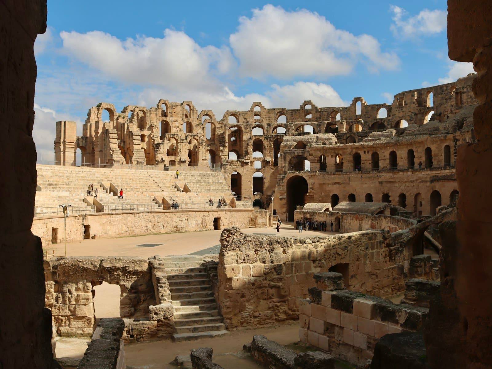 El Djem Amphitheatre — Ancient roman amphitheater ruins under a cloudy sky.