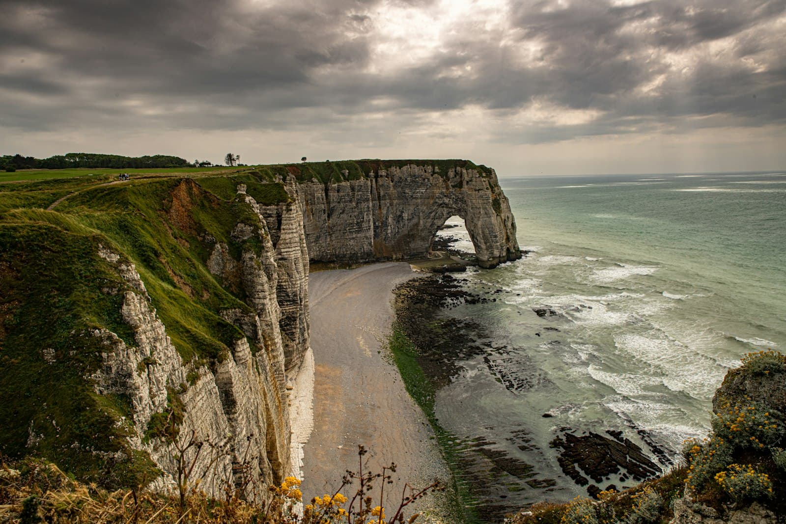 Falaise — a rocky cliff with a beach below it under a cloudy sky