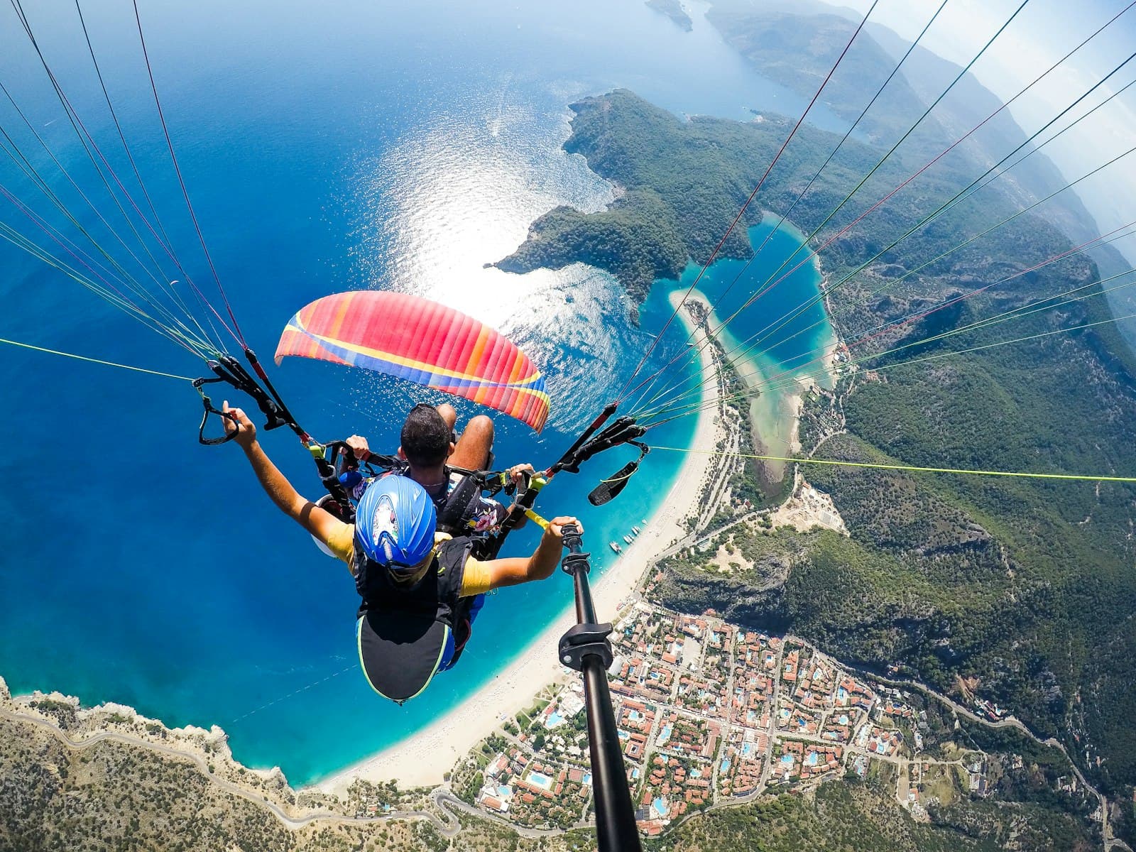 Fethiye — man in blue and black jacket riding on blue and white parachute