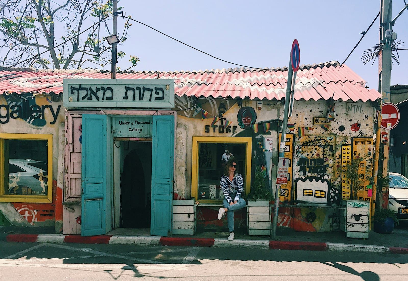 Florentin Street Art — woman sitting beside wooden house