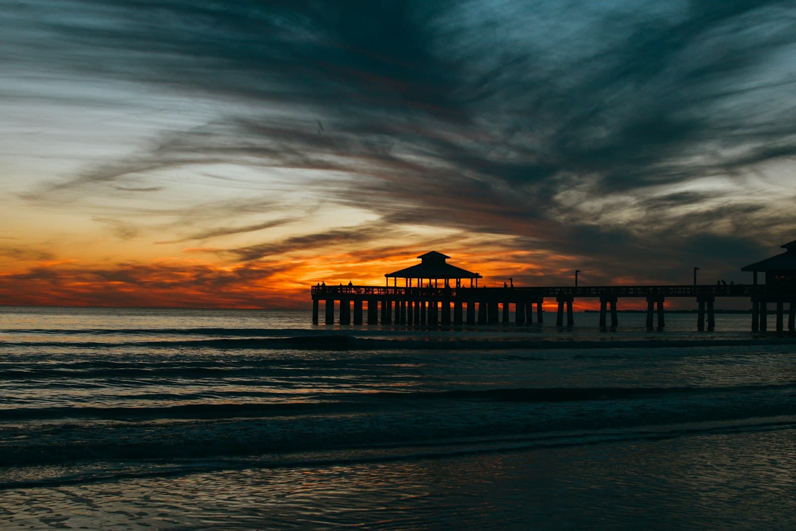 Fort Myers — the sun is setting over the ocean with a pier in the distance