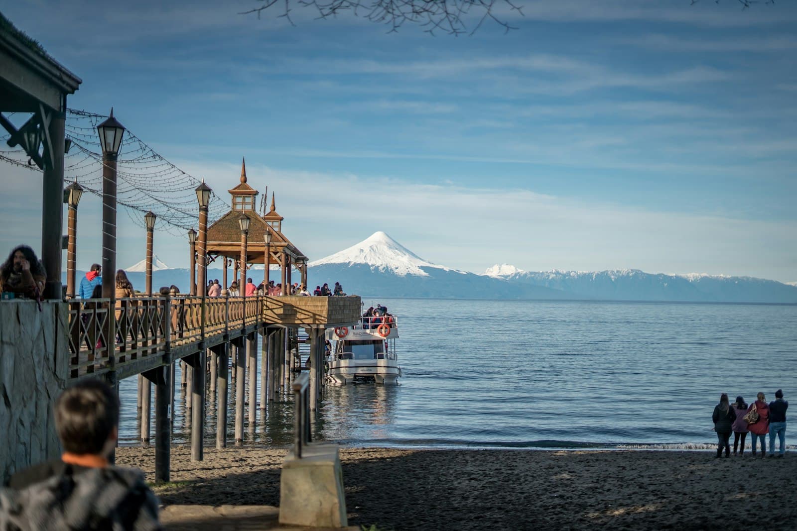Frutillar — a group of people standing on a pier next to a body of water