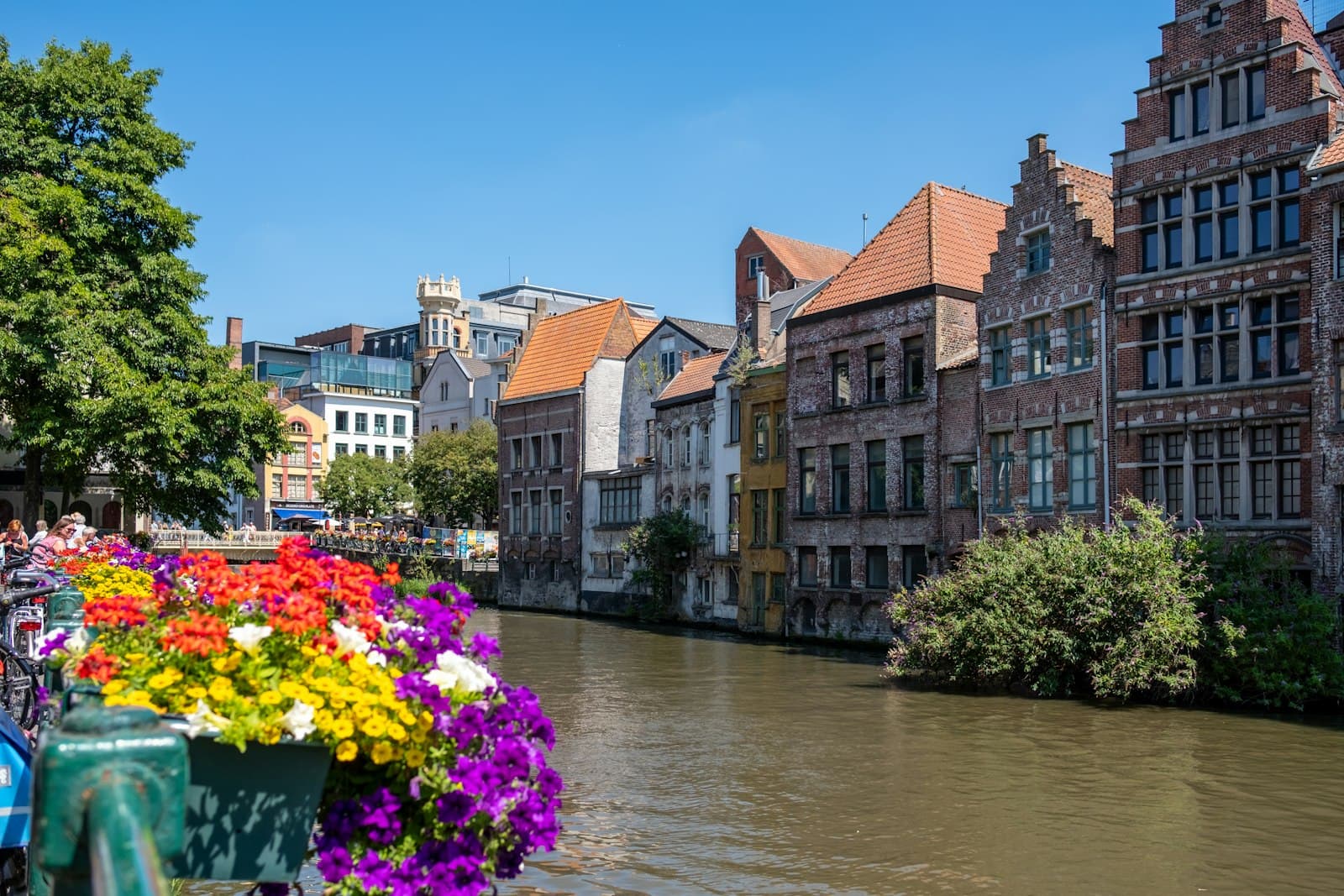 Ghent — brown and white concrete building beside river under blue sky during daytime