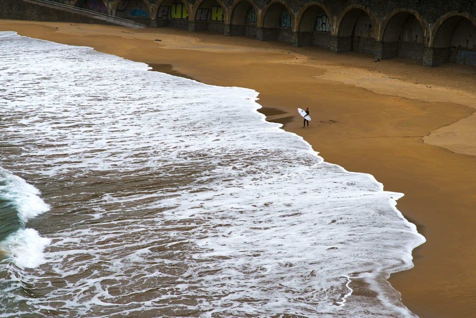 Getaria — A person walking along a beach next to the ocean