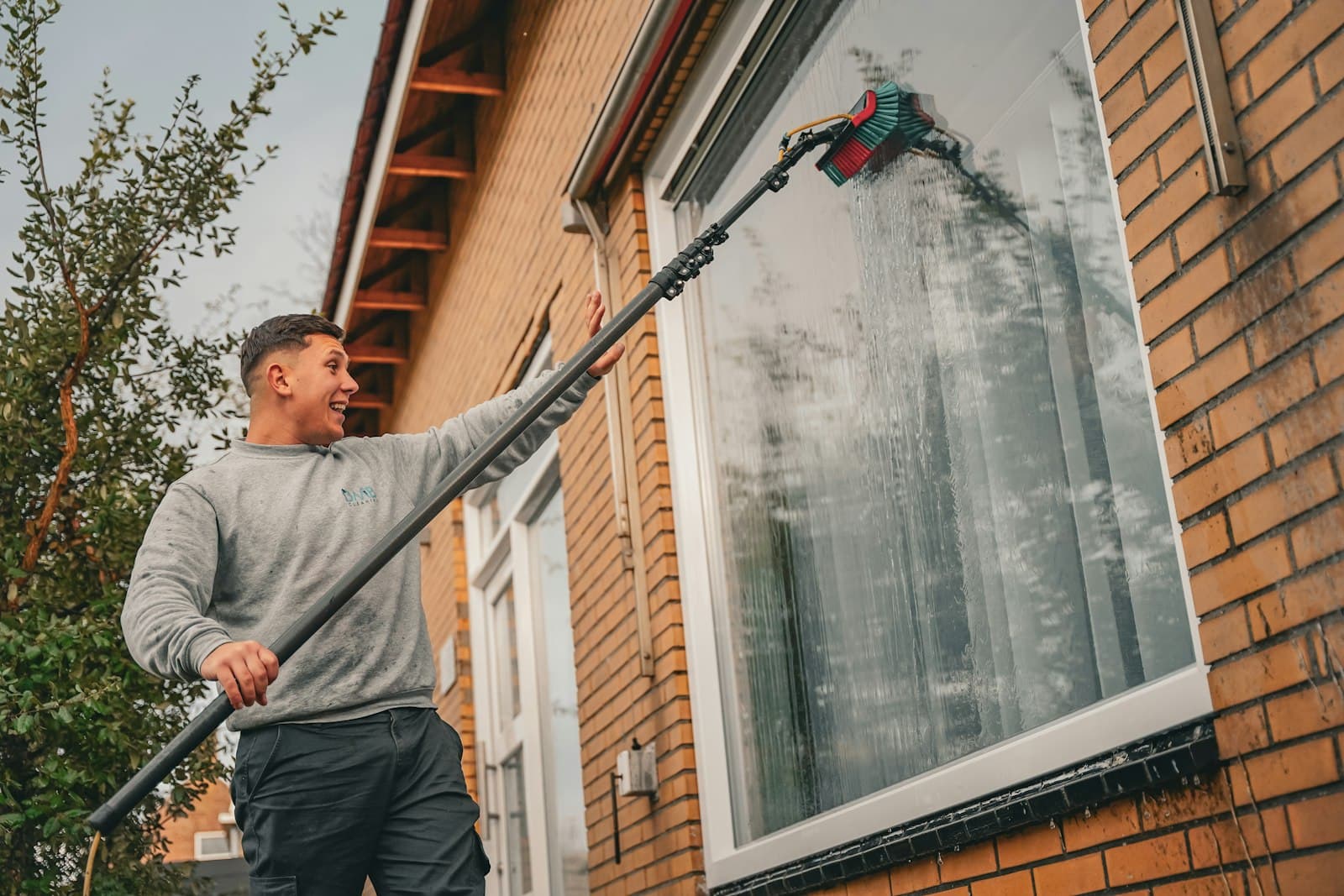 Goes — A man holding a large metal pole in front of a house