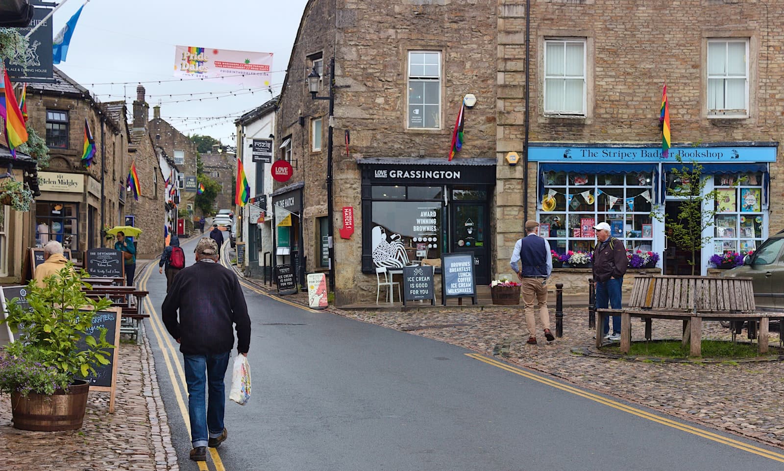 Grassington — a man walking down a street next to a building