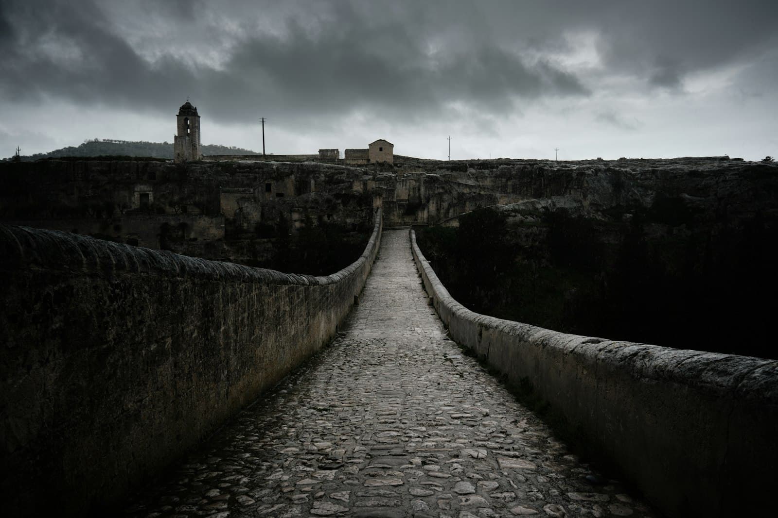 Gravina in Puglia — a stone walkway leading to a castle under a cloudy sky