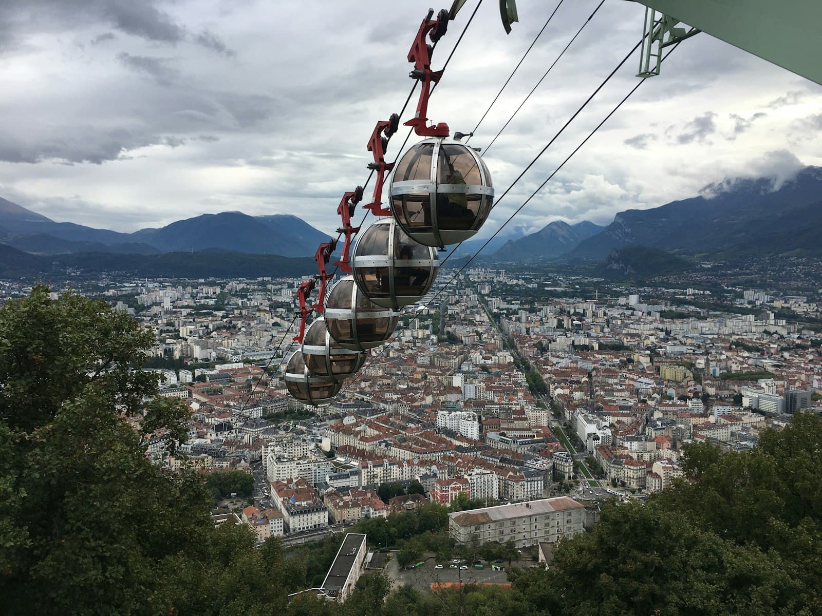 Grenoble — red and black cable car over city during daytime
